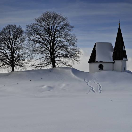 verschneites Feld mit kleiner Kapelle