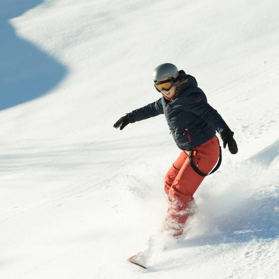 Person fährt mit Snowboard Piste herunter